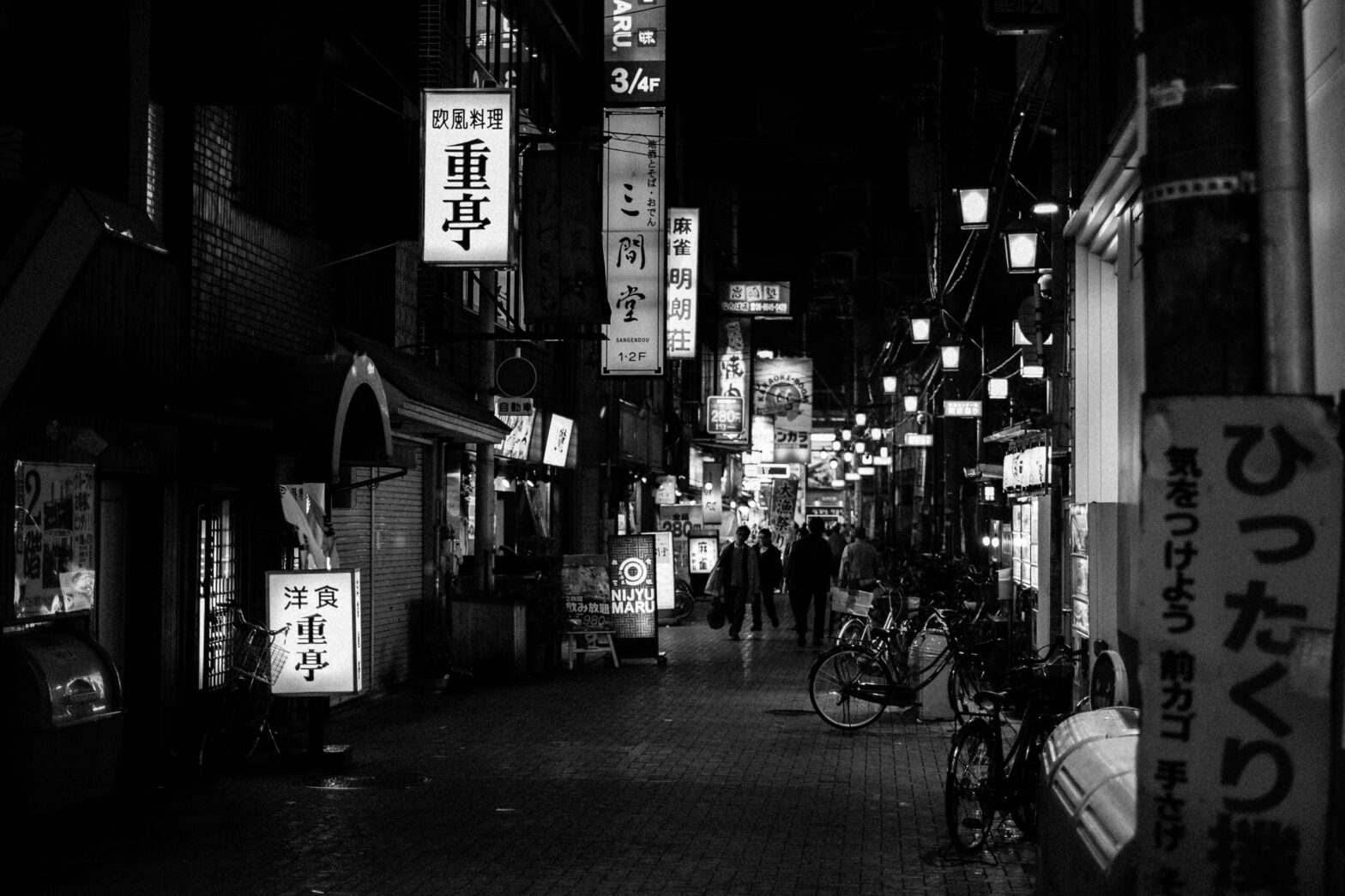 Finding yourself in solitude. A black & white picture of a late night alleyway full of closed shops, bars and restaurants in Osaka, Japan.